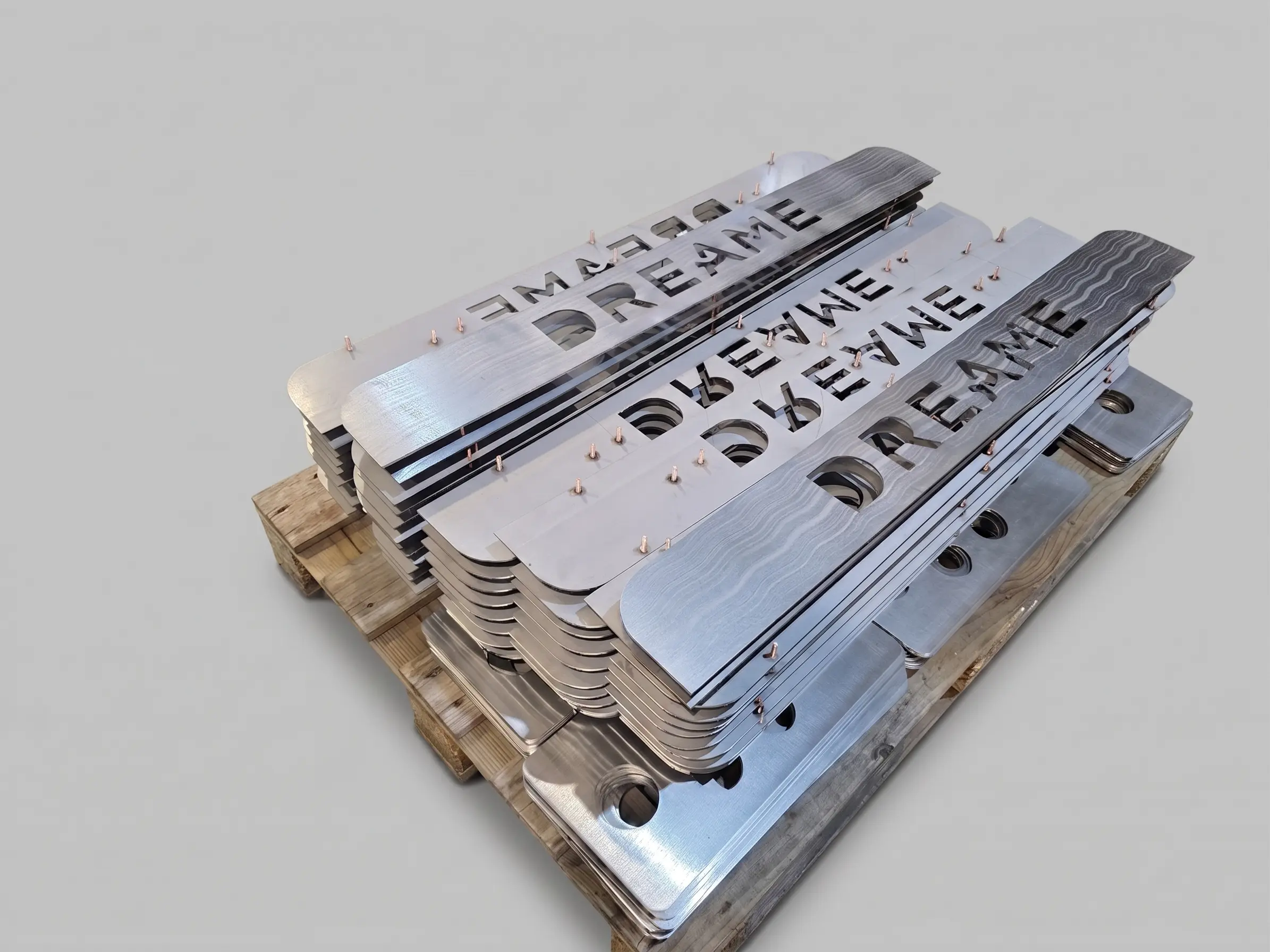 Heavy metal modules with custom engravings, such as 'SMOKE DREAMS', stacked on a wooden pallet
