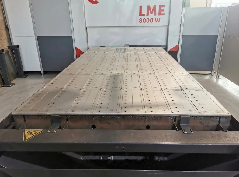 Full sheet with a nesting of freshly cut cover plates, still positioned on the laser cutting machine bed