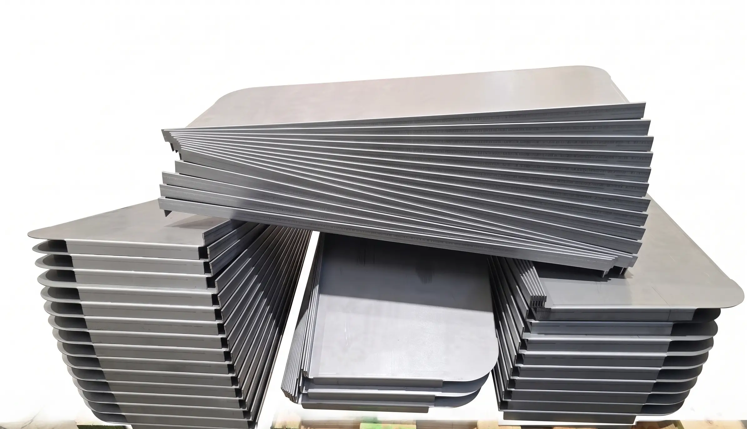 Series of large flat sheet metal panels neatly stacked on a pallet