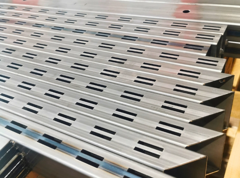 Rectangular section tubes crossed by slots and multiple rows of precision holes