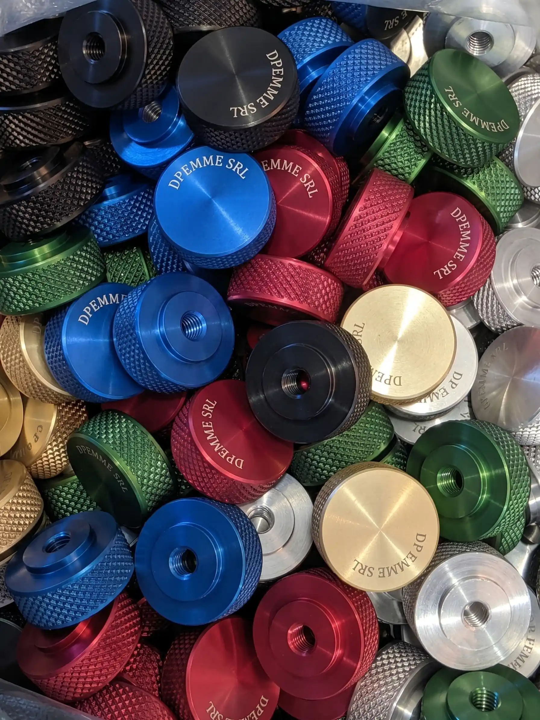 Insieme di pulsanti e manopole in alluminio lavorato, anodizzati in rosso, verde, blu, oro e nero, su uno sfondo scuro - 2
